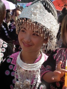 A young Hmong girl smiles in the morning sun. Her elaborate headdress and necklace is made of pure silver, which is how the Hmong people store their wealth. They do not have banks - the Hmong New Year is the only time of the year they all come out to display all their wealth.